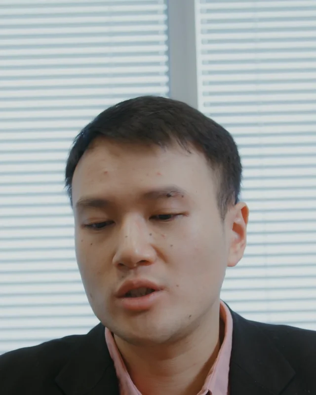 Webcam view: a man looking down at his notes while speaking